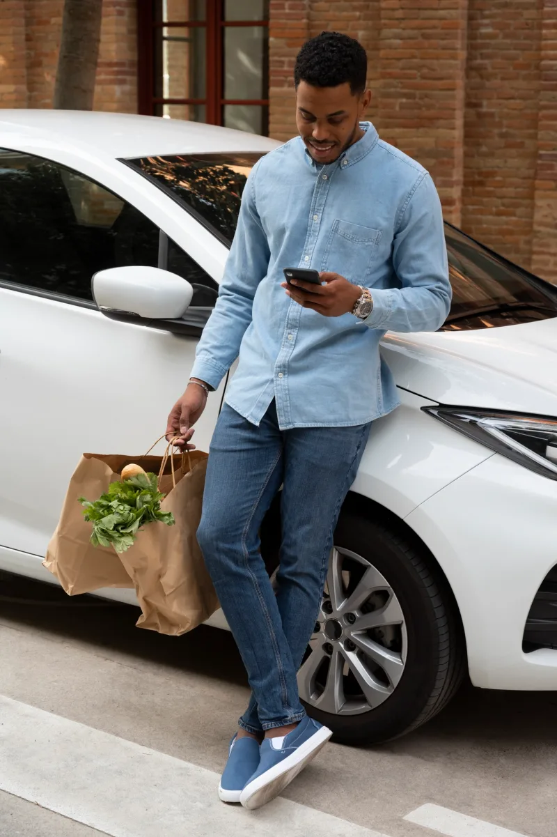 Man with groceries leaning on a car