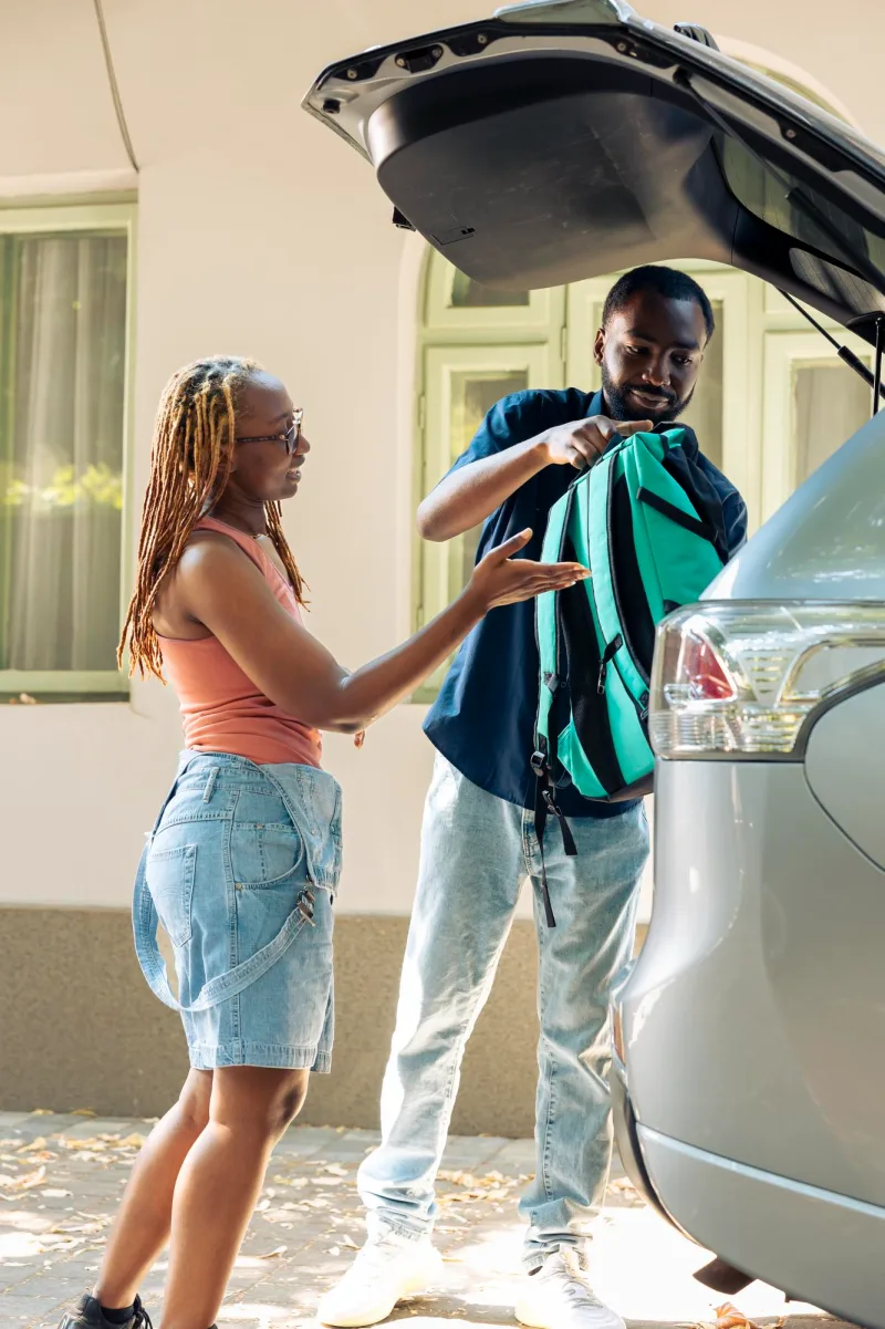 Couple loading a backpack into a car trunk